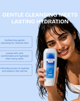 Woman holding a bottle of skincare product with text about gentle cleansing and lasting hydration on a light blue background.