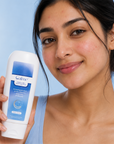 Woman holding a Calme lotion bottle against a blue background